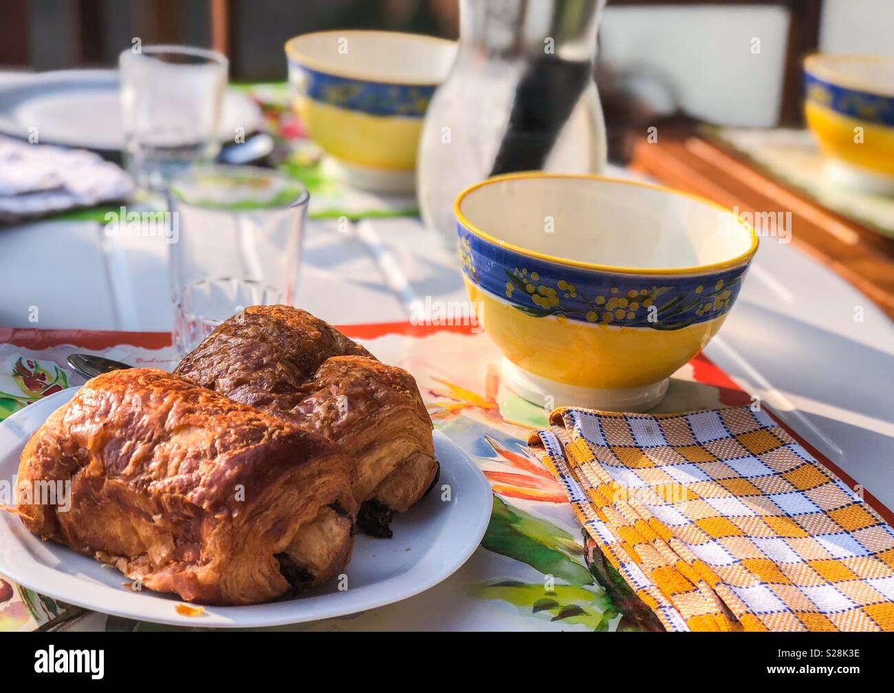 Ein Foto von einem traditionellen französischen Frühstück mit Pain au Chocolat, Kaffee Schüssel und Servietten Stockfoto