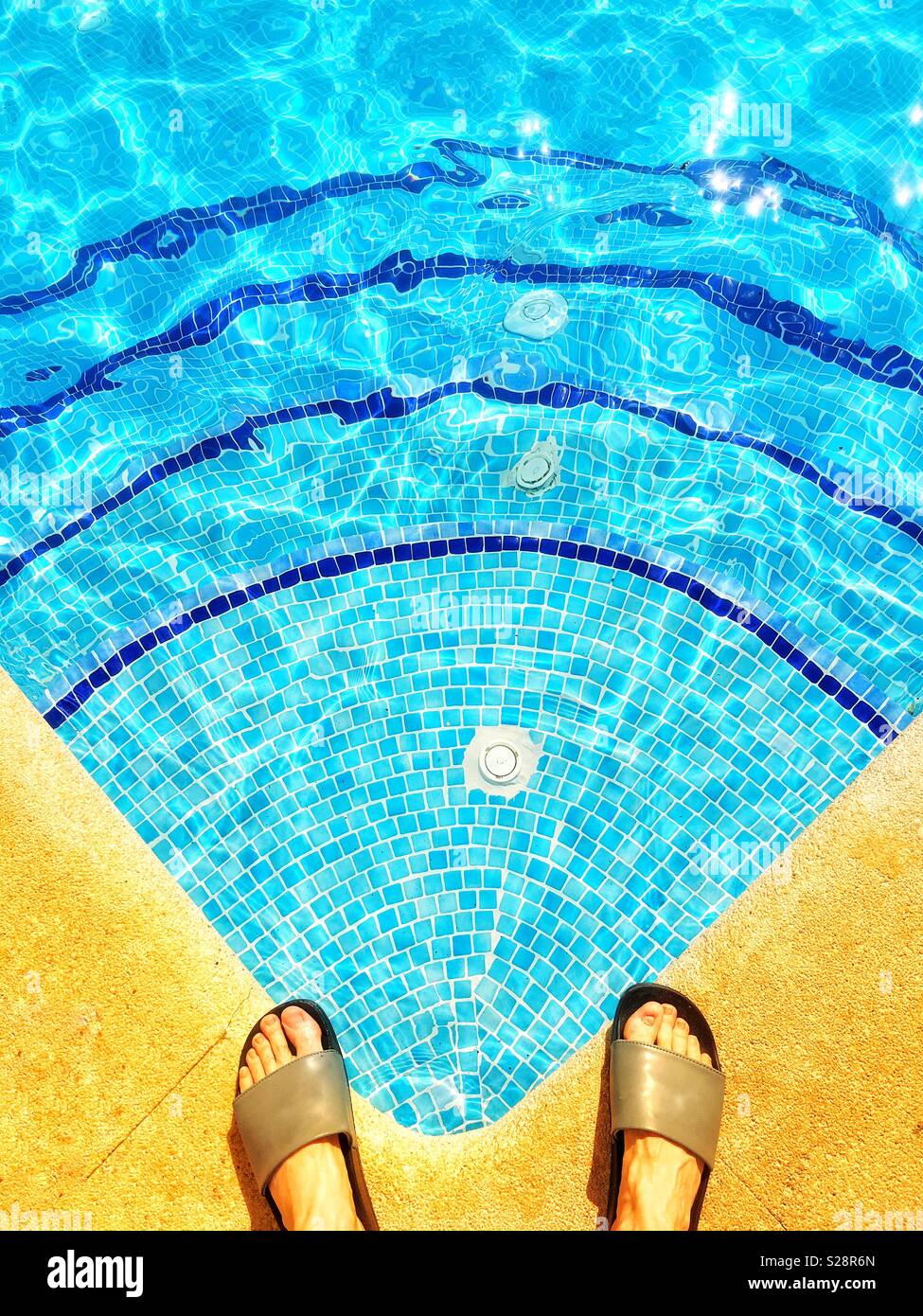 Füße im Slip auf Schuhen (Schieberegler) am Rand des Pools Stockfoto