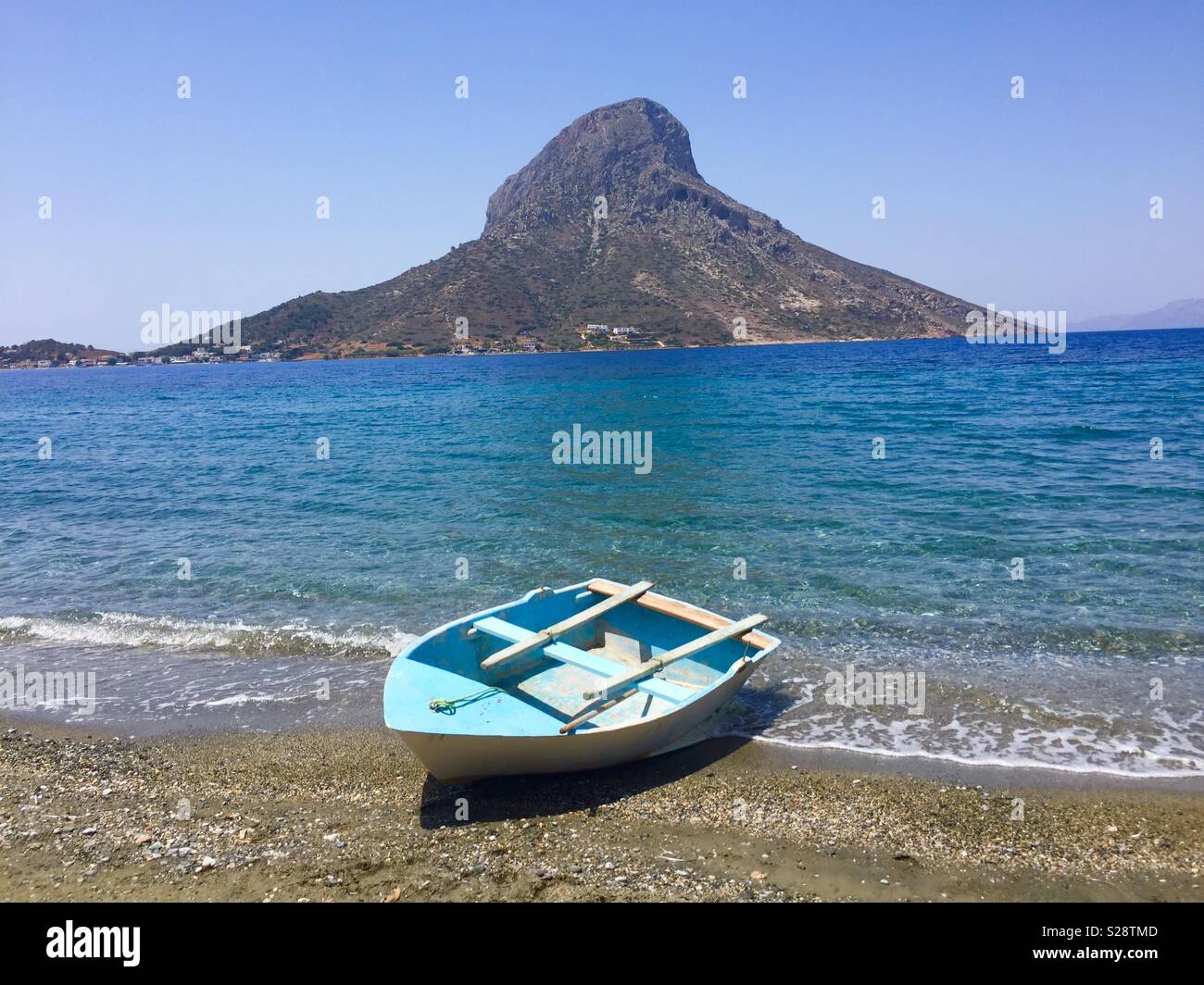 Kleines, blaues Ruderboot auf einem Strand in Kalymnos - mit Blick auf die Insel Telendos Stockfoto