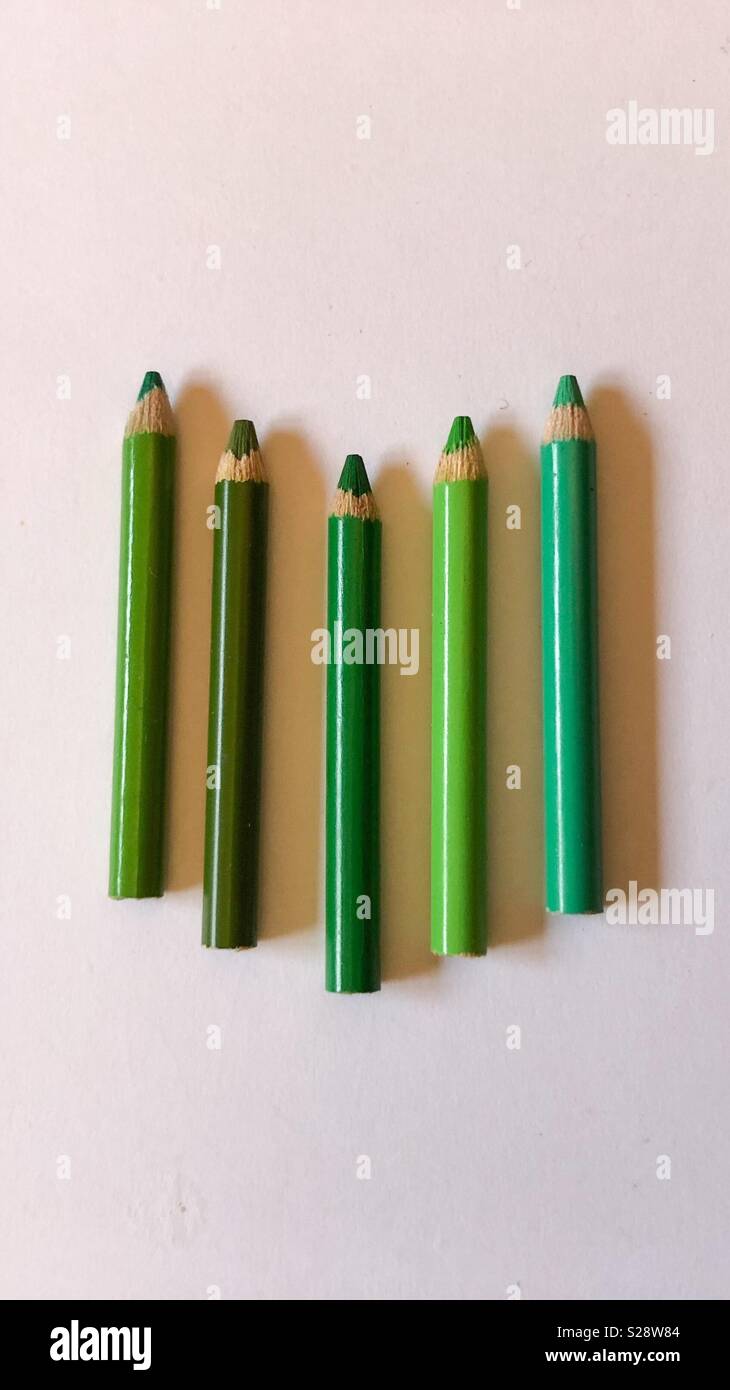 Grüne kleine Bleistifte in der Mitte mit verschiedenen Steigungen auf weißem Hintergrund Stockfoto