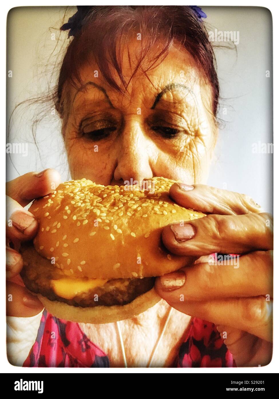 Ältere Frau essen Käse Burger Stockfoto