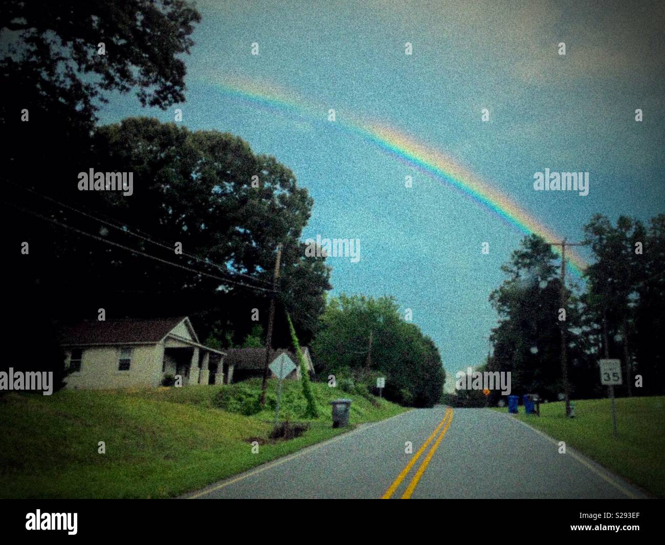 Regenbogen über Wohngebiet und Straße Stockfoto