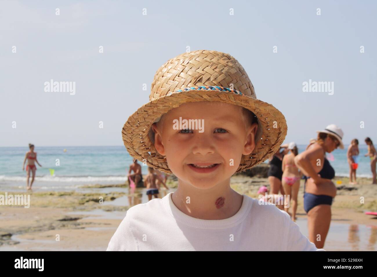Junge trägt einen Strohhut auf einem Strand Stockfoto