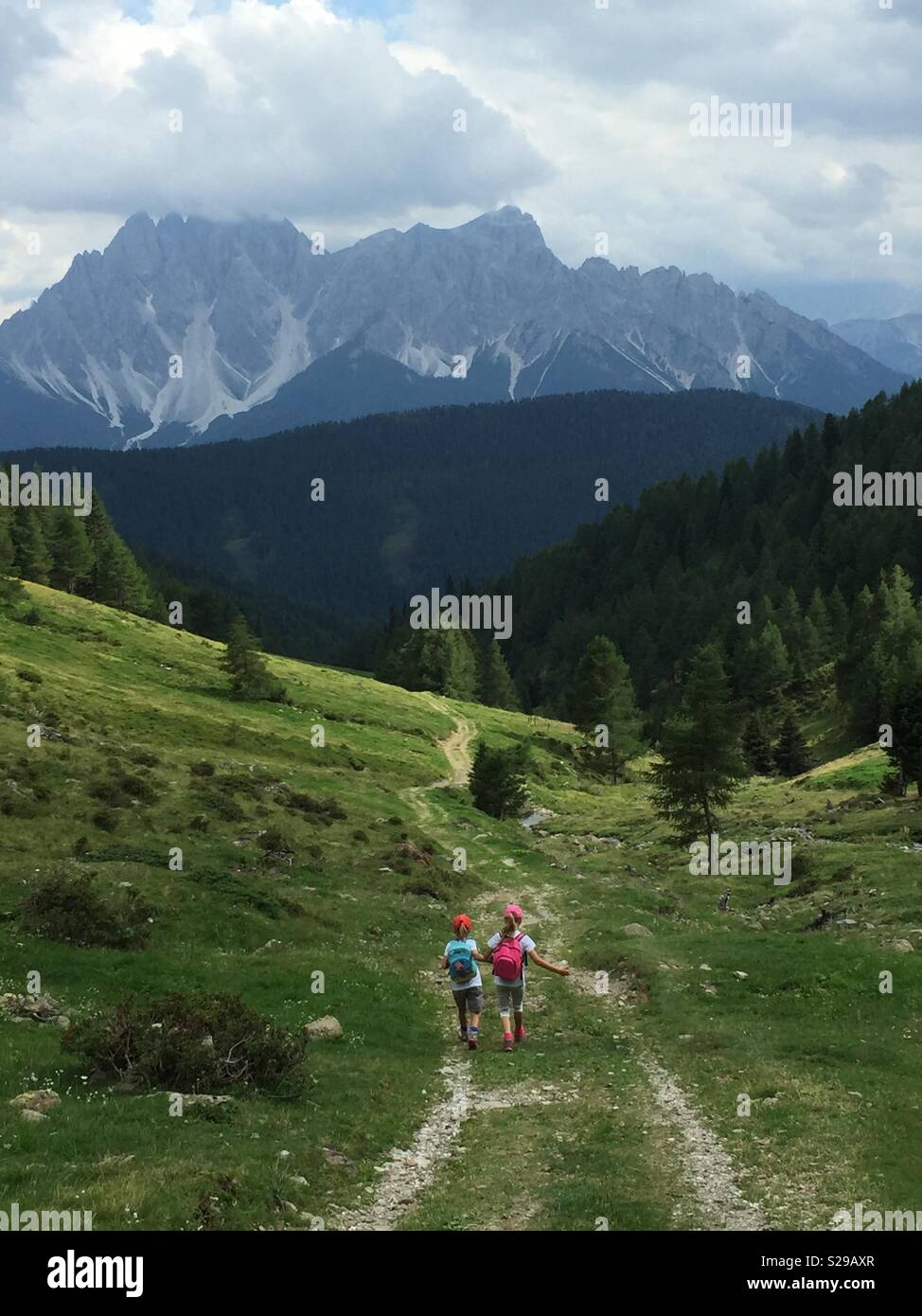 Schwestern gingen Hand in Hand auf einem Berg Trail. - Smartphone-aufgenommenes Stockfoto