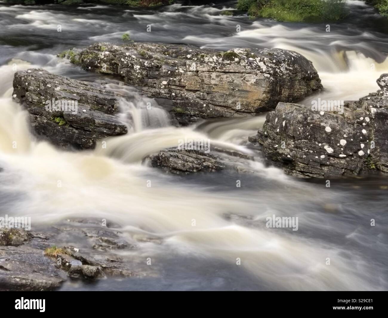 Nahaufnahme von Invermoriston fällt, Schottland, mit Felsen und lange exposer Wasser fließt. Stockfoto