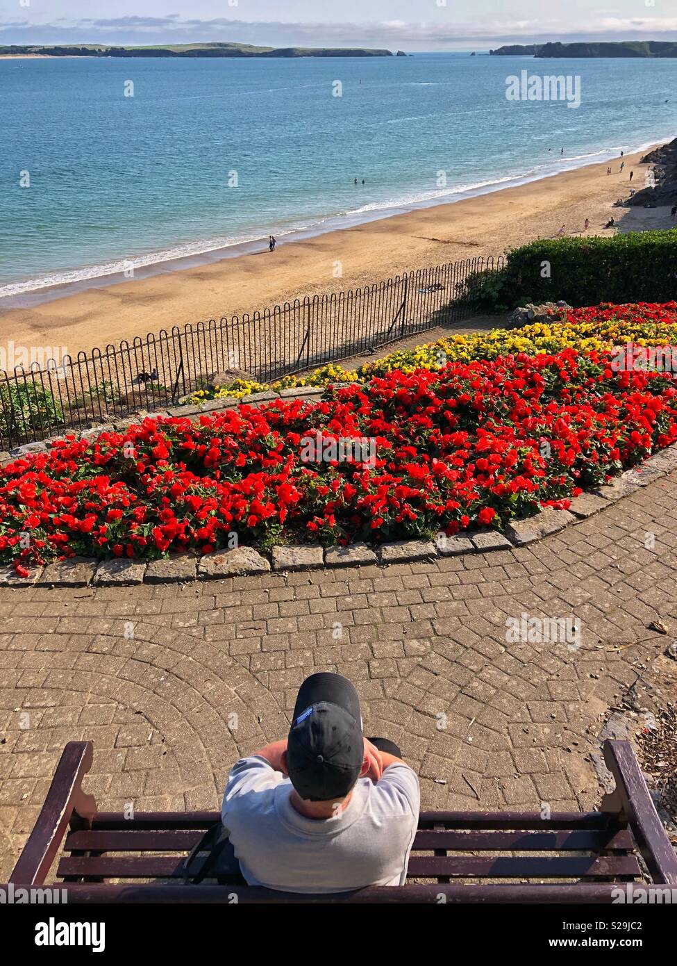 Ein Mann genießt die Aussicht über Tenby South Beach, Tenby, West Wales. Stockfoto