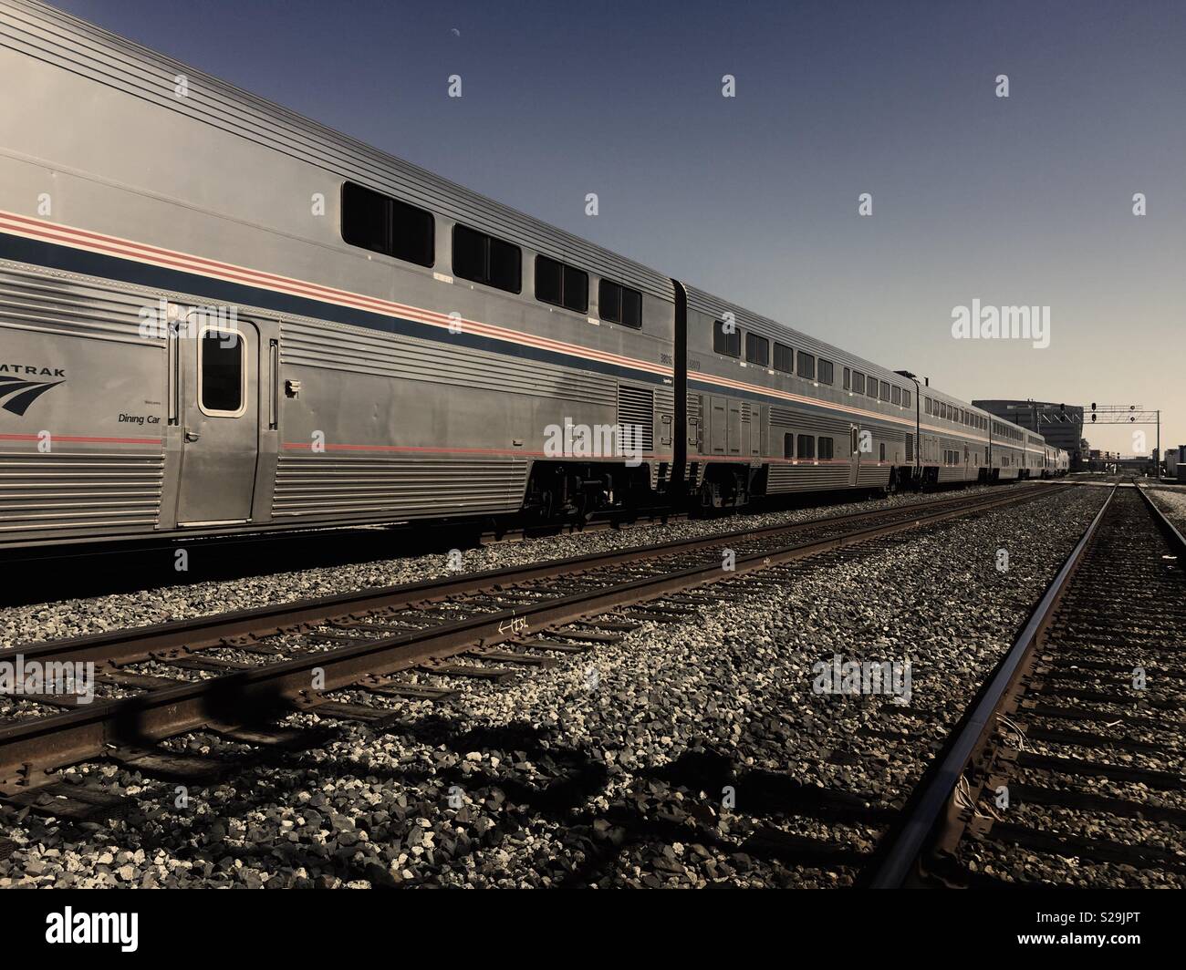 Länge des Amtrak-Personenzugs aus der tiefen Perspektive zum Fluchtpunkt, neben leeren Eisenbahnschienen. Emeryville, Kalifornien. Stockfoto