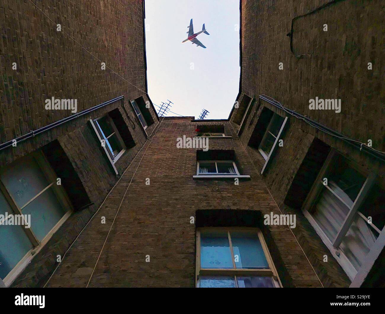 Tief fliegenden Flugzeug über Apartment Blocks in London Stockfoto