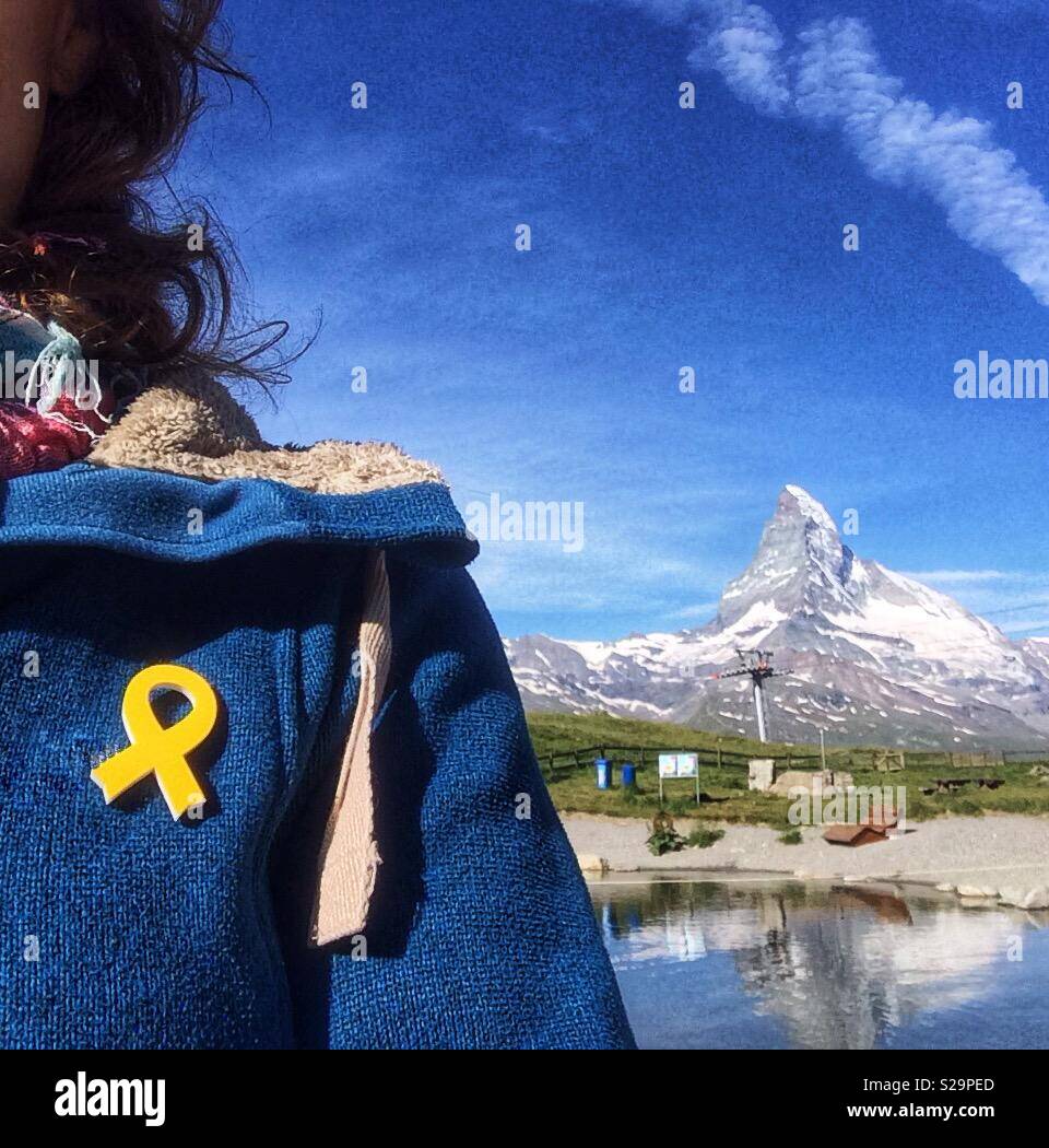 Katalanisch Tourist mit einem gelben Band in ihren blauen zur Unterstützung des Inhaftierten pro aufgebockt angeheftet - Unabhängigkeit katalanischer Politiker. Blick auf das Matterhorn, Zermatt, Wallis oder Wallis, Schweiz. Stockfoto