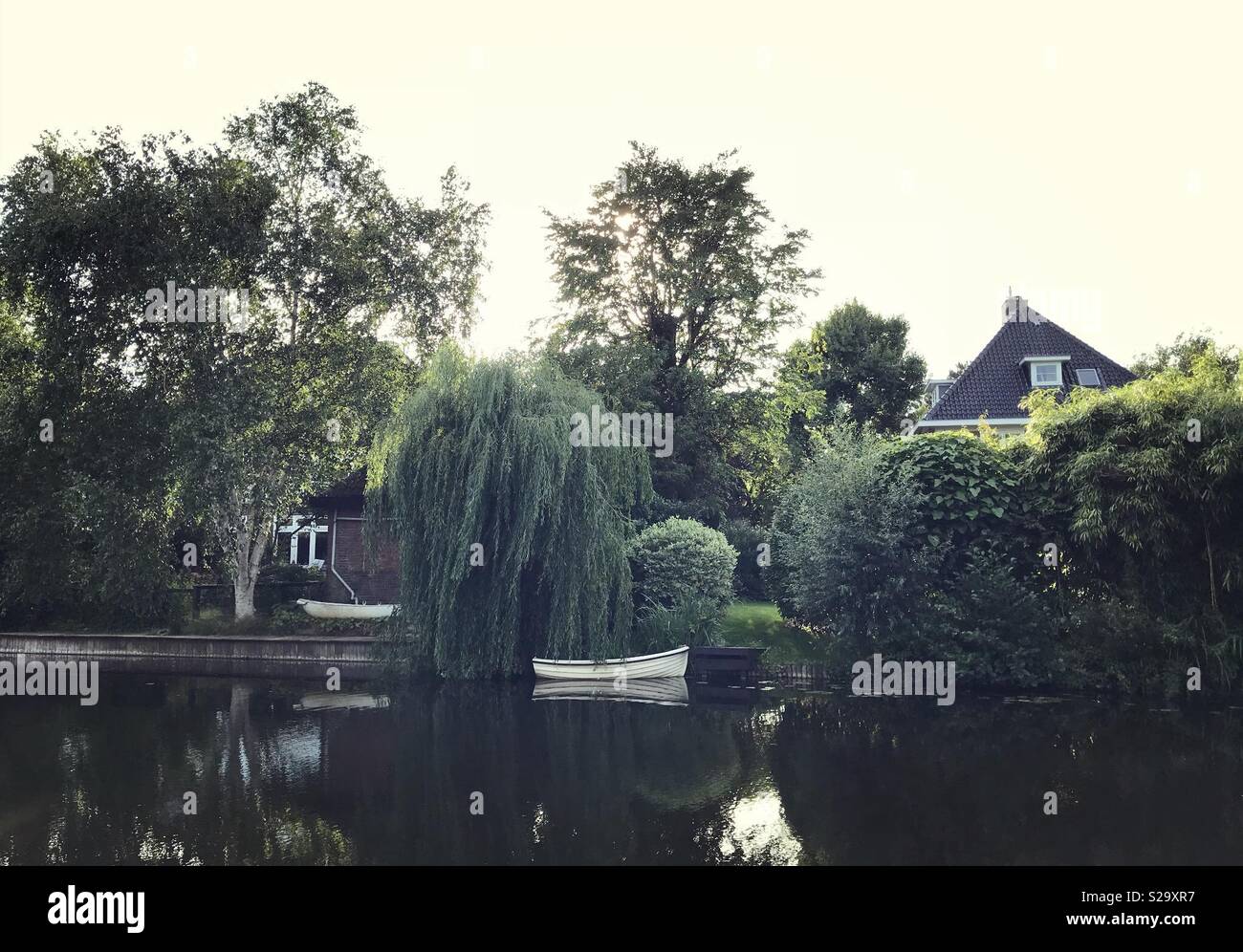 Kanal durch Haus und Boot unter dem Willow Tree Eingang - Smartphone-aufgenommenes Stockfoto