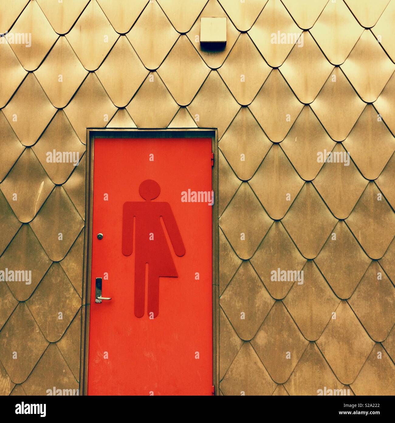 Ein rotes unisex WC-Tür auf einem Gold - gender Flüssigkeit/gender-neutral/transgender Symbol Stockfoto