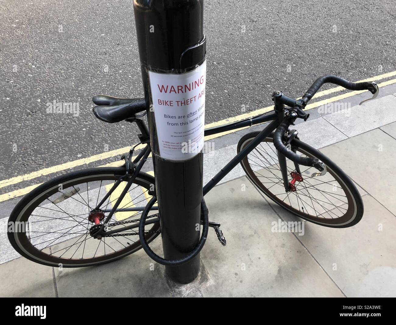Angekettete Fahrrad neben Warnung Fahrrad Diebstahl anmelden London Stockfoto