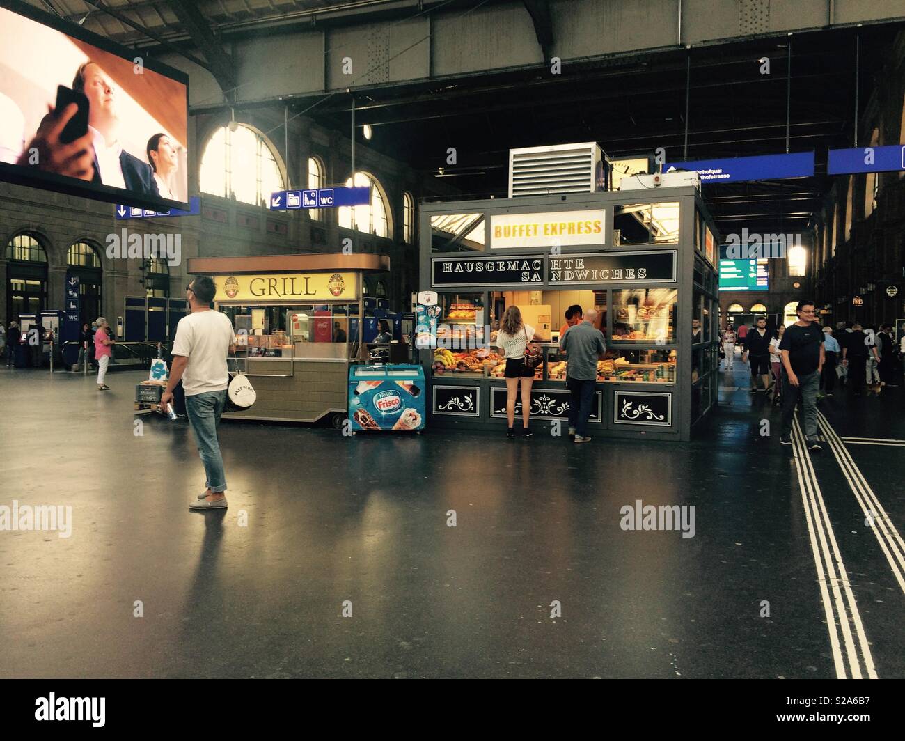 Pendler im Zürcher Hauptbahnhof oder Bahnhof Erfrischungen an einem Kiosk für Ihre Zugfahrt kaufen - Smartphone-aufgenommenes Stockfoto