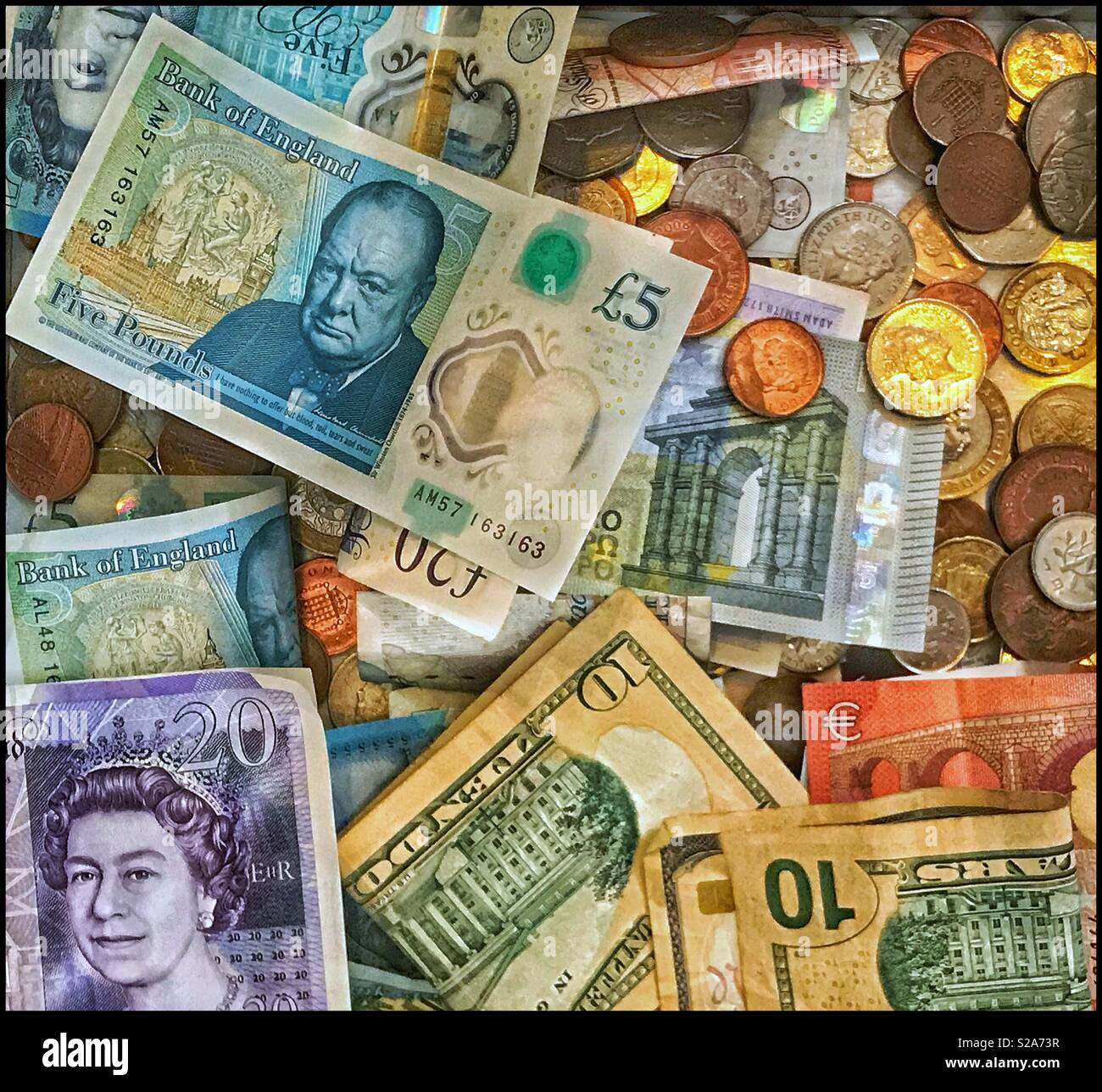 Eine Sammlung von verschiedenen Banknoten und Münzen. Deutlich sichtbar sind die 24 Pfund Sterling Hinweis, der neue fünf Pfund Sterling Hinweis und die zehn US-Dollar Note/Rechnung. Ein Bild für die globale Wirtschaft. Stockfoto