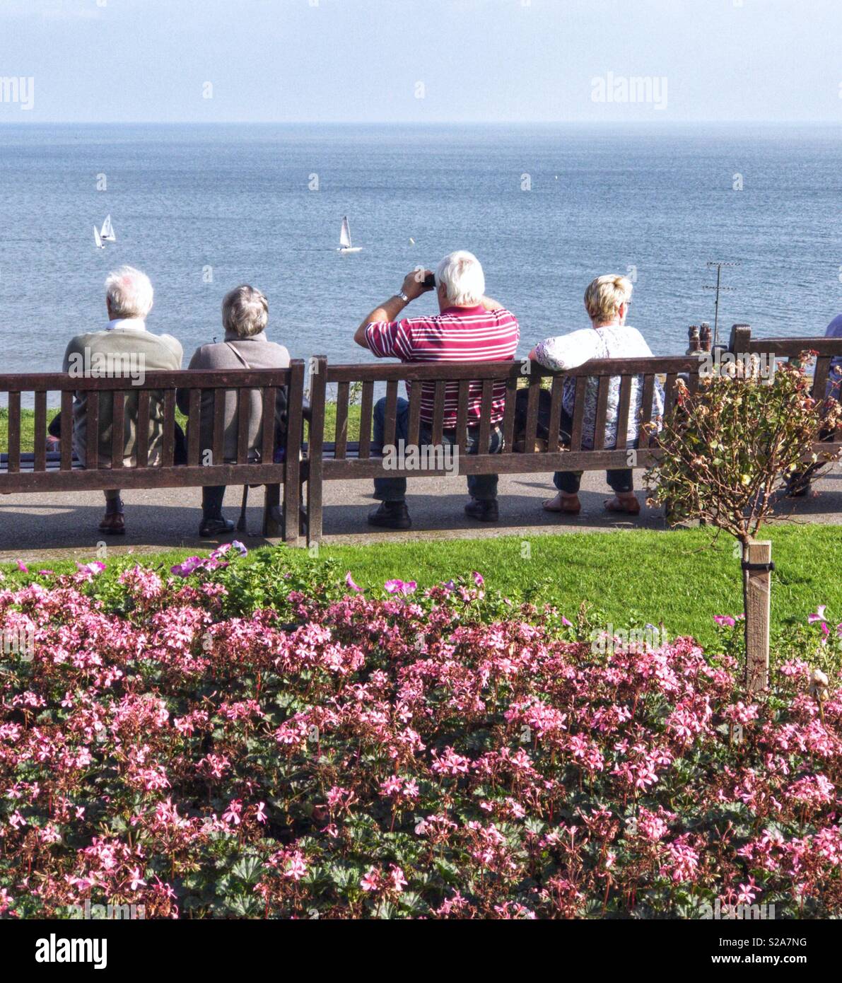 Pensionierte Paare auf einer Klippe Sitzbank mit Blick auf das Meer in England Stockfoto