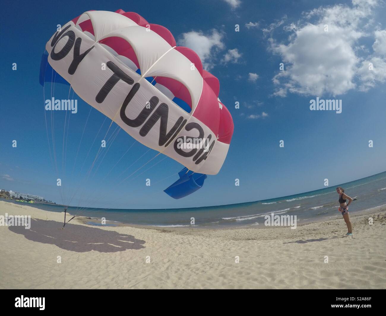 Ein Gleitschirm Schreibwaren auf einem Strand mit einer Dame, die darauf wartet auf den Strand für eine Fliege Fahrt zu nehmen Stockfoto