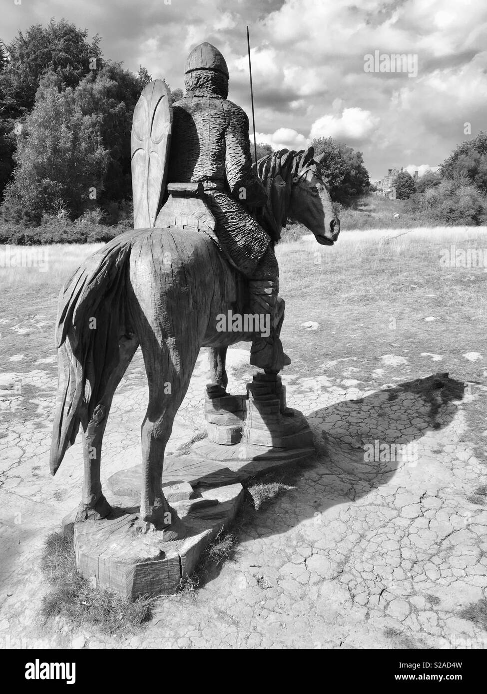 Vorwärts in die Schlacht (Holz Skulptur eines normannischen Soldaten zu Pferd, an der Stelle der Schlacht von Hastings, mit Battle Abbey im Hintergrund) Stockfoto