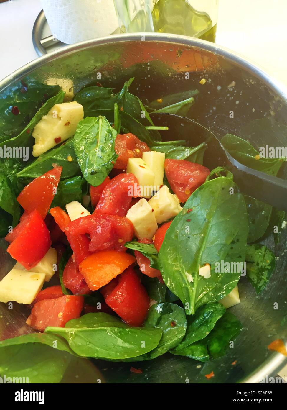 Frisch Spinat Salat mit Olivenöl, heirloom Tomaten und Parmesan bröckelt geworfen Stockfoto