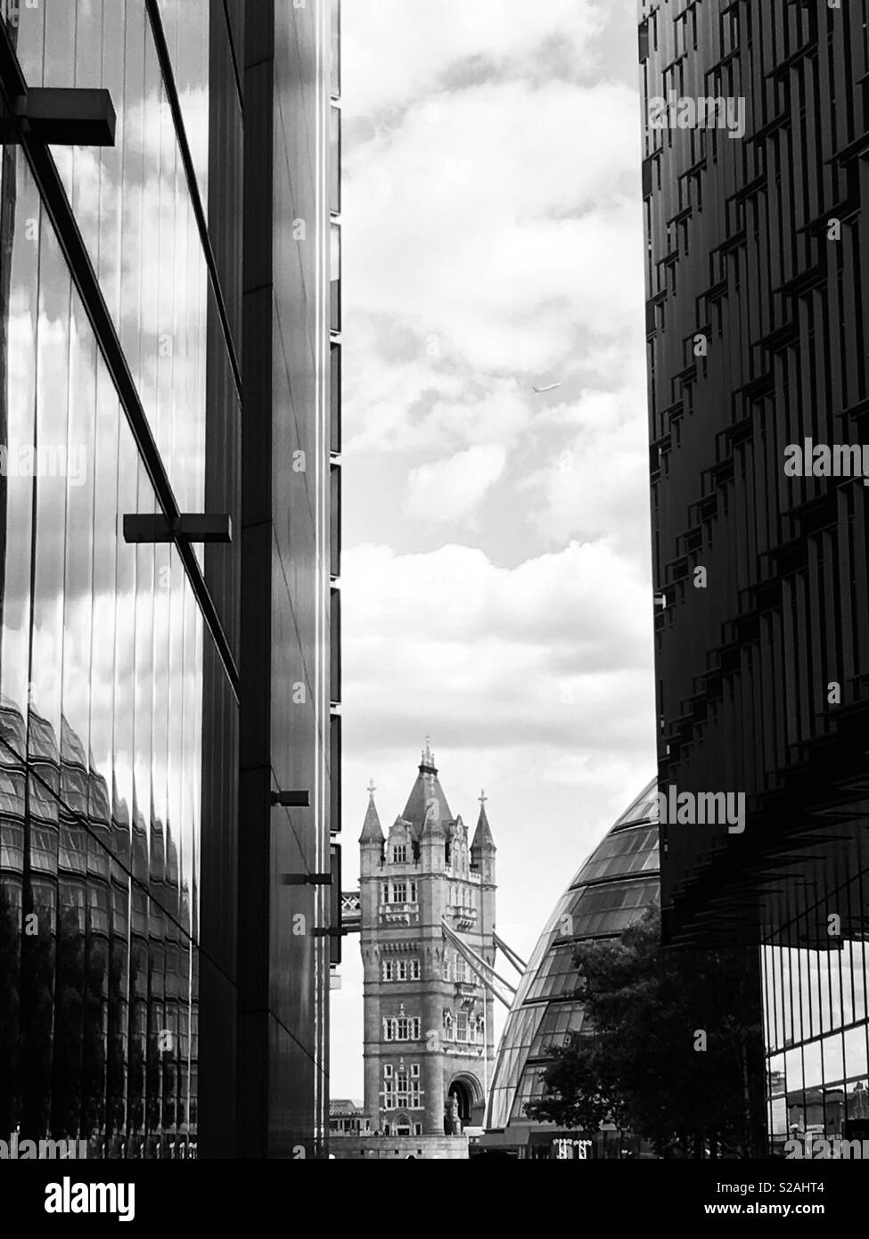 Die Tower Bridge und die City Hall, London, glimpsed durch Glas Gebäude in Schwarz und Weiß. Stockfoto