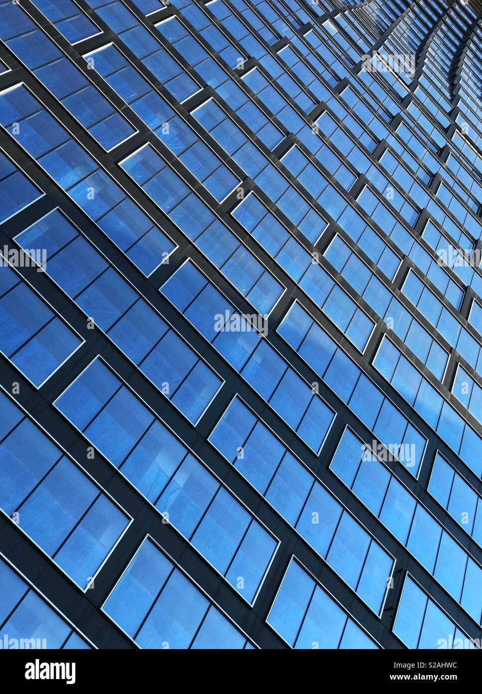Muster von Windows, die den blauen Himmel, auf ein neues Hochhaus in der Innenstadt von Calgary, Alberta, Kanada. - Smartphone-aufgenommenes Stockfoto