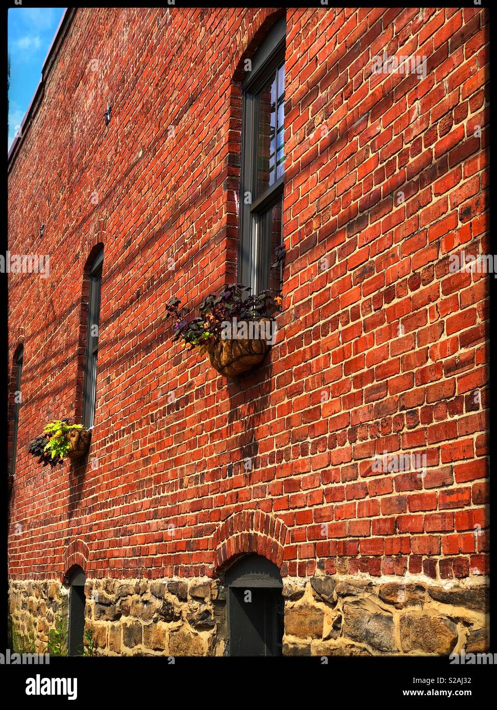 Hängende Bügeleisen Pflanzer aus einem alten Backsteingebäude Stockfoto