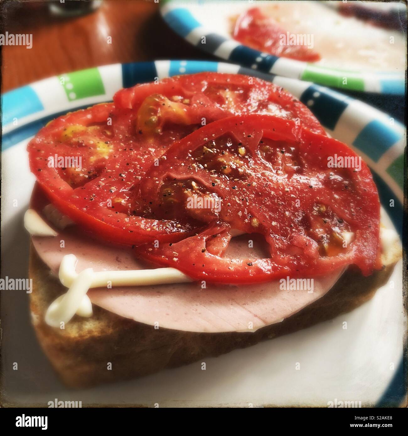 In Scheiben geschnittene Tomaten auf Bologna und Mayonnaise Sandwich, über Hipstamatic. - Smartphone-aufgenommenes Stockfoto