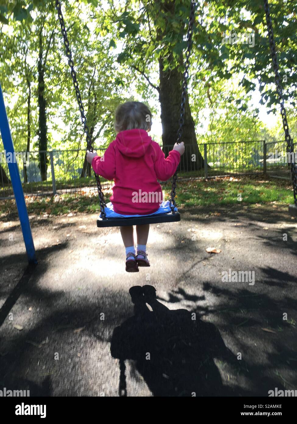 Vier Jahre altes Mädchen Schwingen auf der Schaukel in einem Swing Park. Großbritannien - Smartphone-aufgenommenes Stockfoto