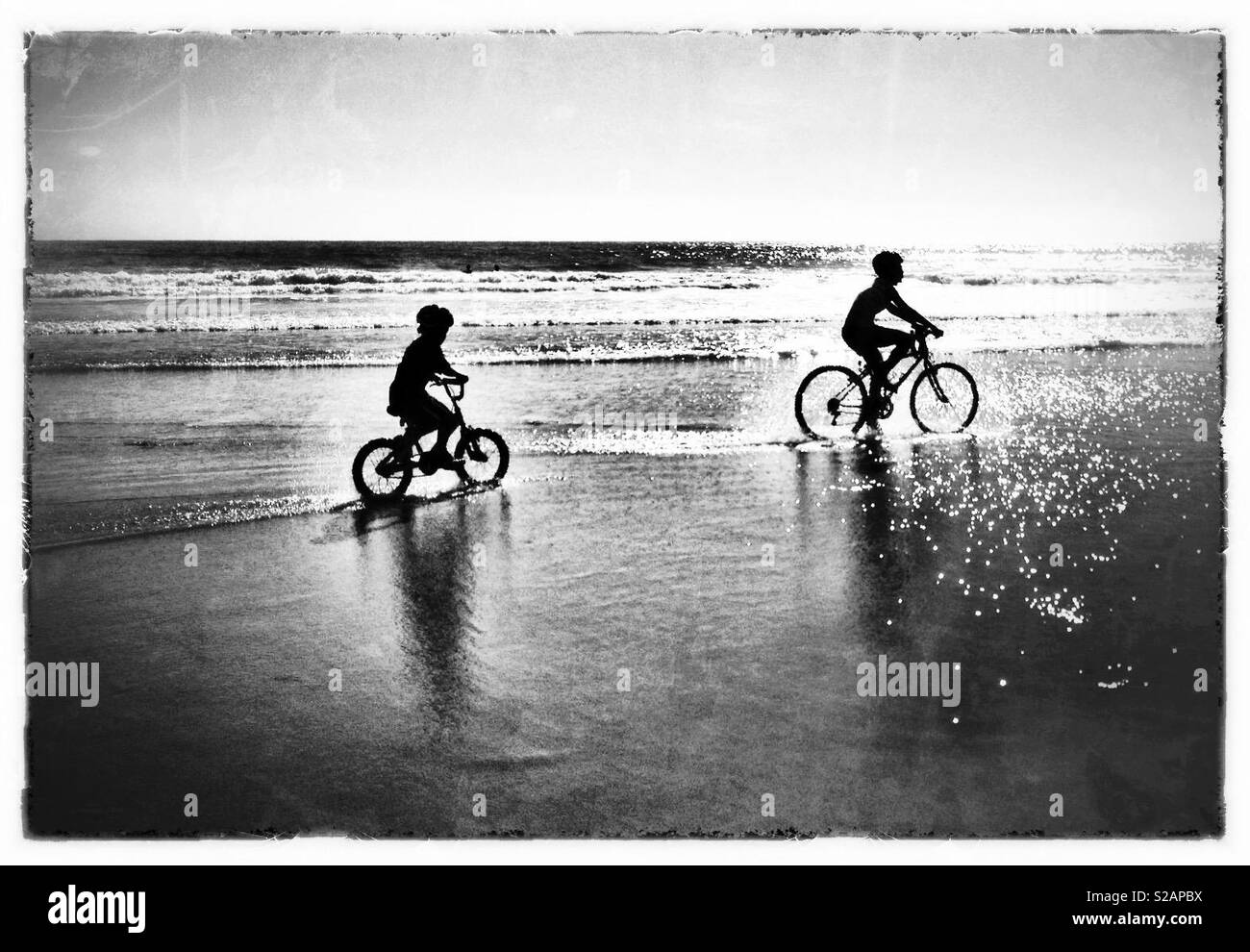 Bruder und Schwester Fahrrad am Strand bei Sonnenuntergang. Stockfoto