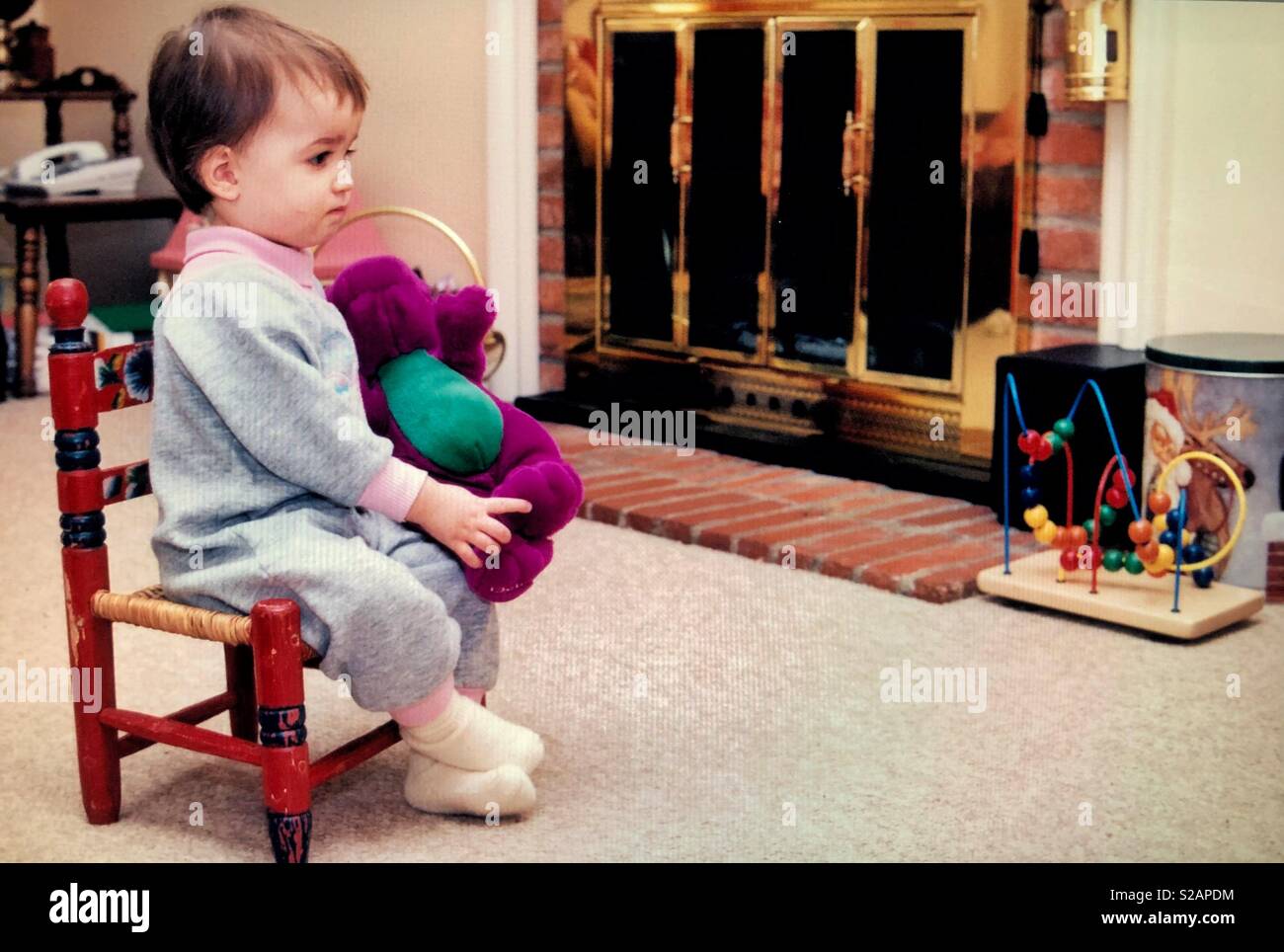 Ein säugling Kleinkind Mädchen in einem Stuhl mit einem ausgestopften  Dinosaurier und vor dem Fernseher sitzen Stockfotografie - Alamy
