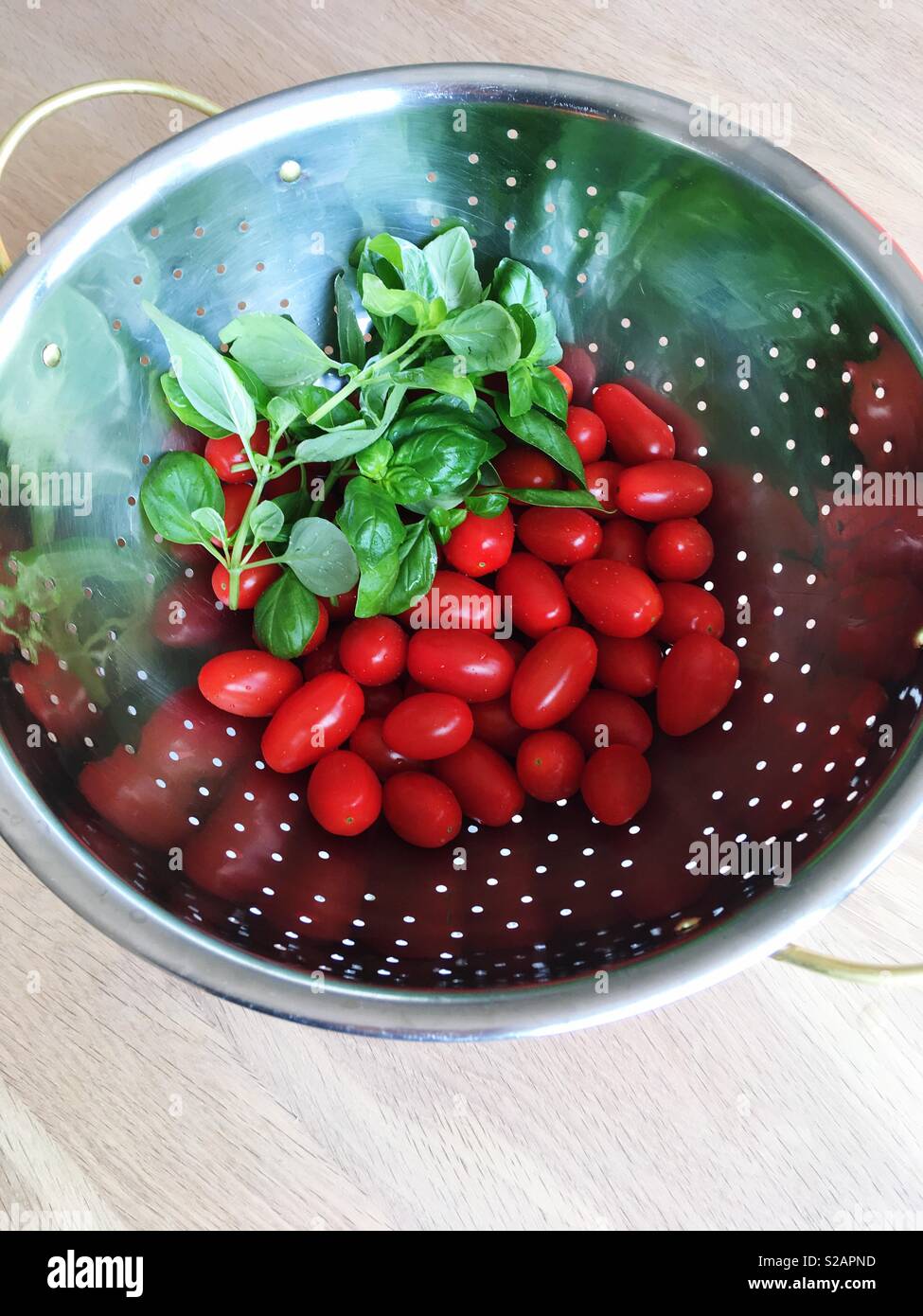 Tomaten und Basilikum in einem metallsieb Stockfoto