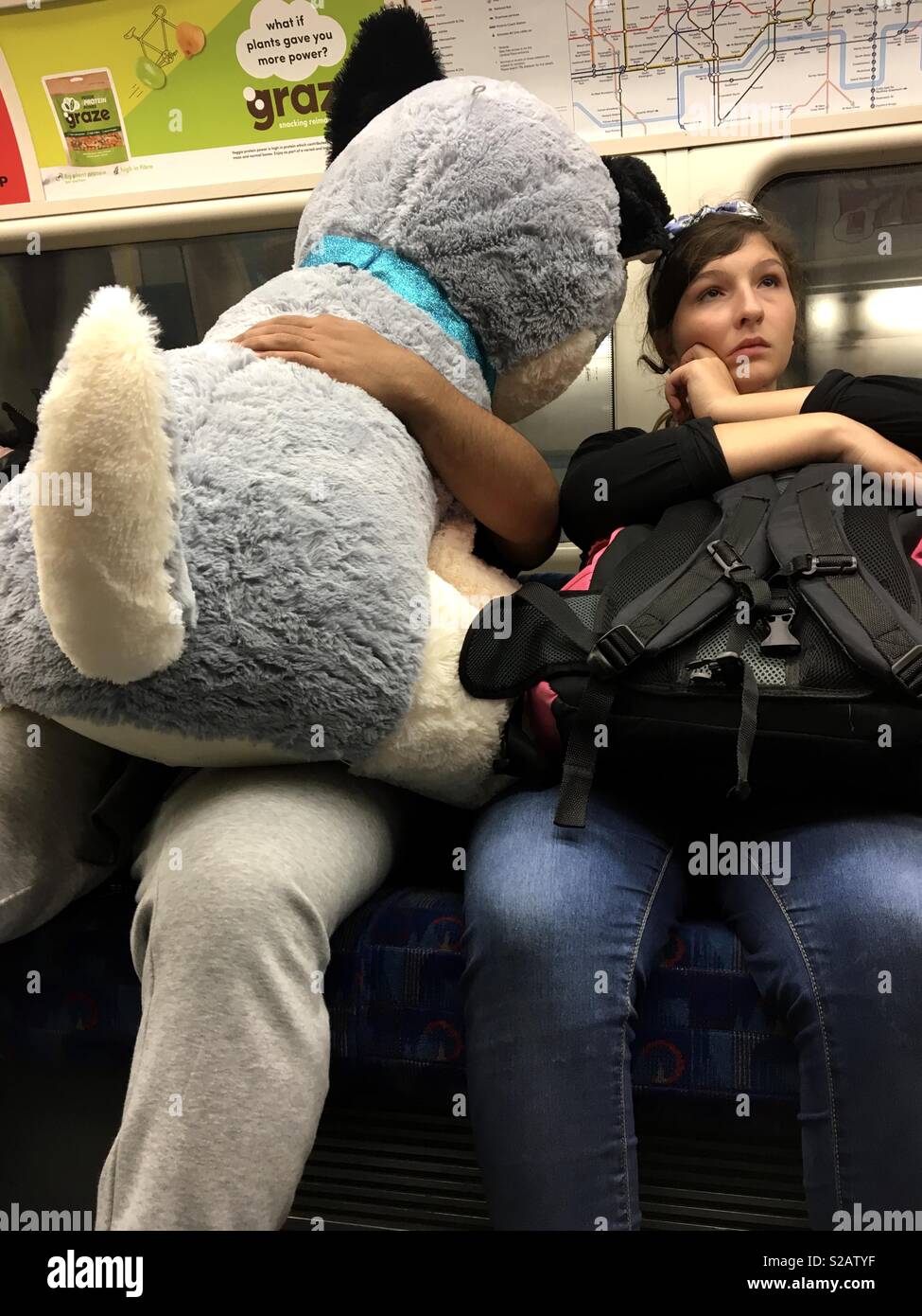 Frau auf dem Rohr mit der Londoner U-Bahn saß neben einem riesigen ausgestopften Hund in unmittelbarer Nähe. Sie sieht aus wie Sie Ihre nächste Reise planen Stockfoto