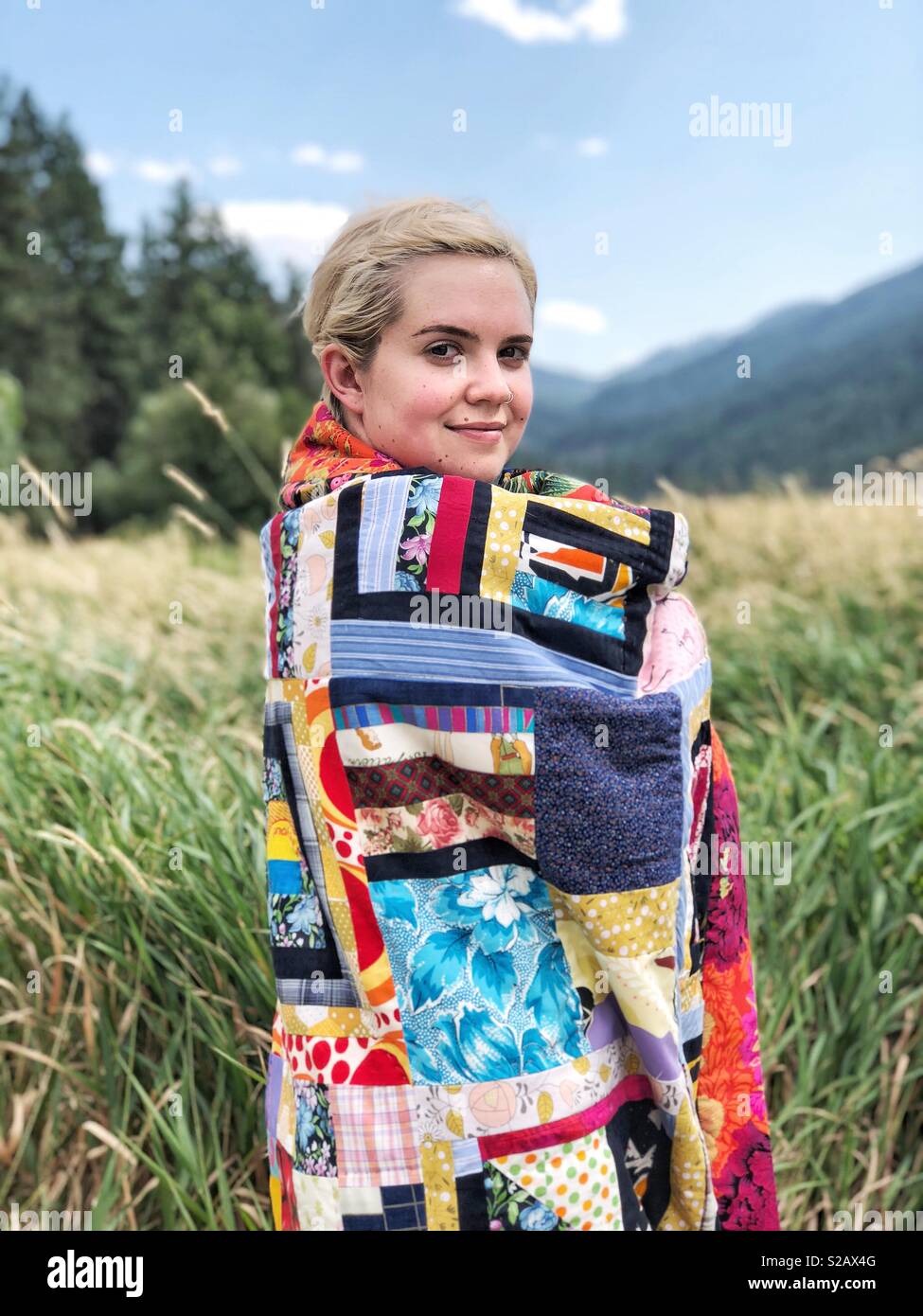 Mädchen verpackt in Modern Quilt Decke in der Wiese Stockfoto