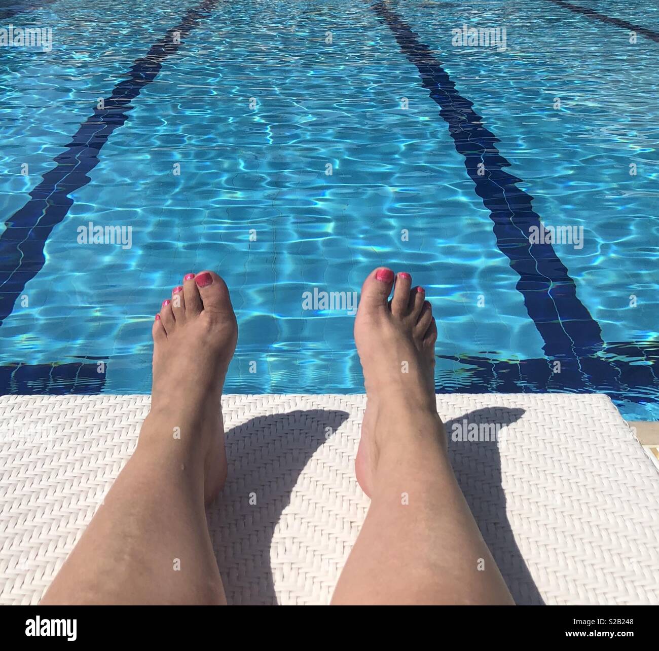 Lady ruht auf einem Liegestuhl in der Nähe von einem Pool Stockfoto