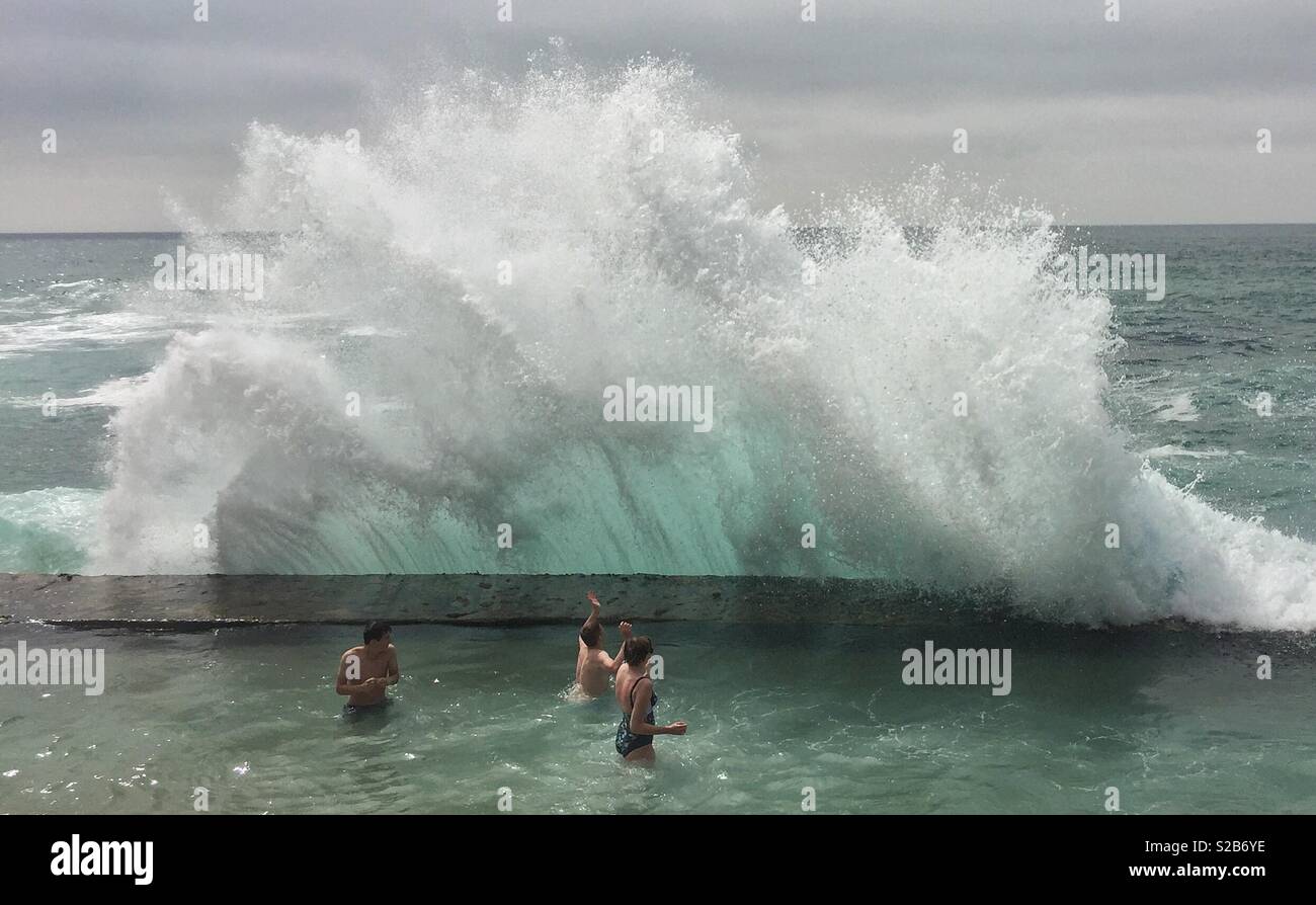 Riesige Wellen brechen über Sea Wall in Meer Pool über 3 Menschen in Portugal Stockfoto