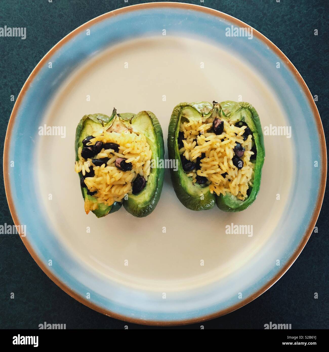 Grüne Paprika gefüllt mit karibischer Reis und schwarze Bohnen auf einer Platte Stockfoto