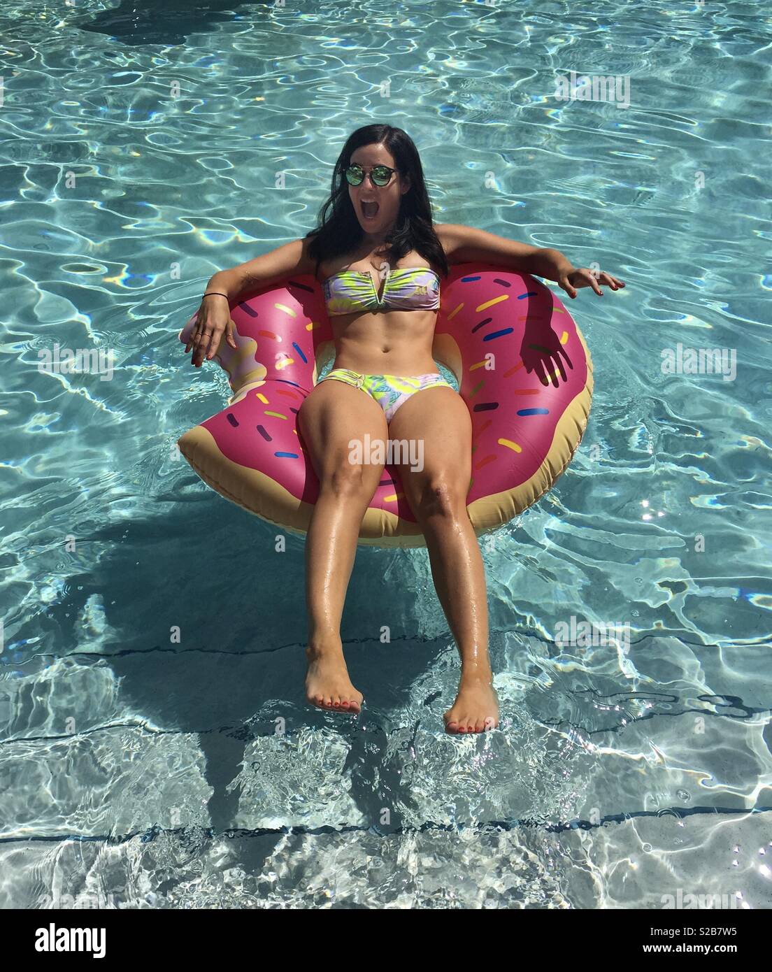 Schöne junge Frau ins kalte Wasser springen auf Donut pool Float Stockfoto