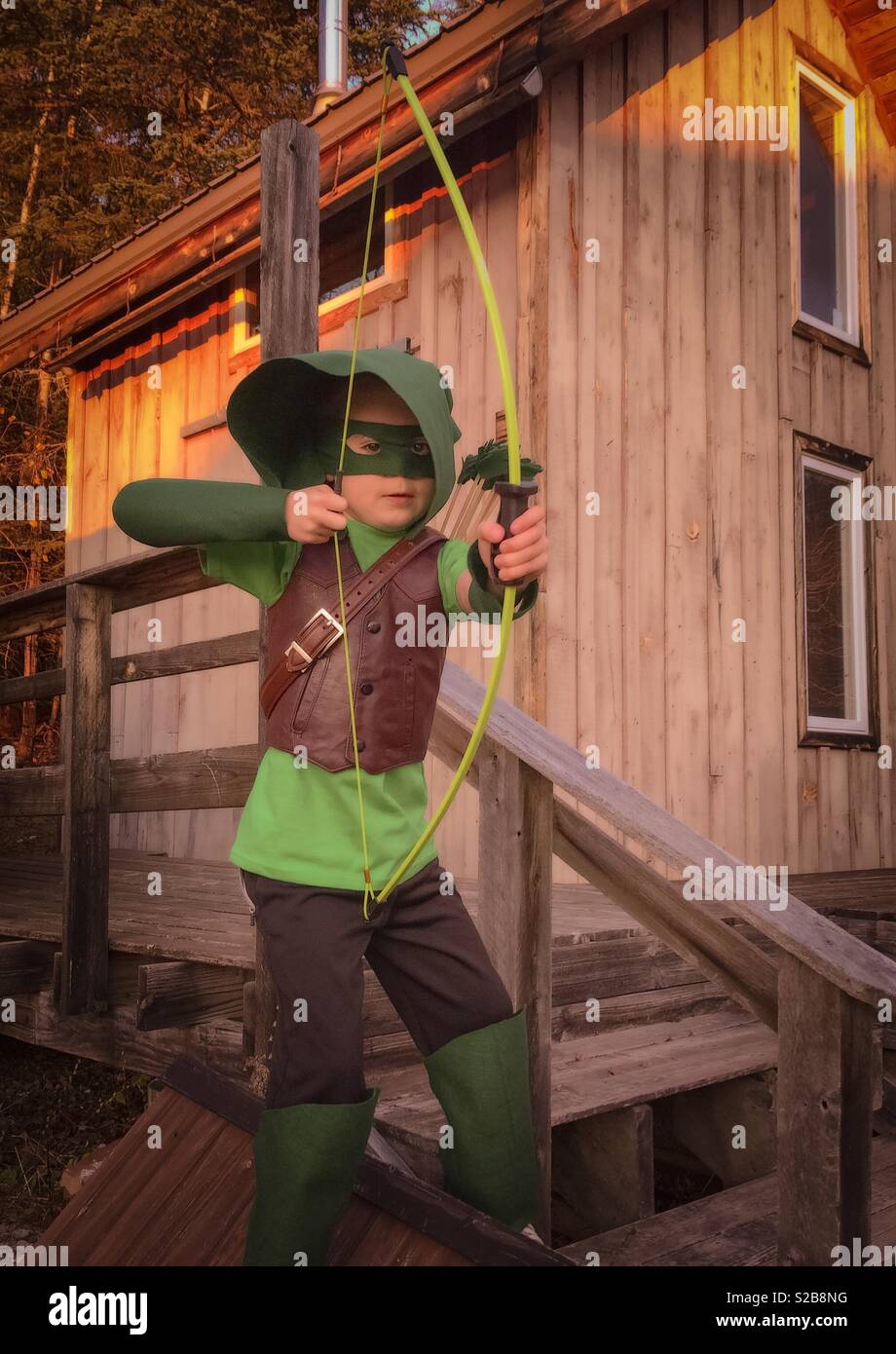 Ein sieben Jahre alter Junge wirft in seinem grünen Pfeil Kostüm für Halloween. Stockfoto