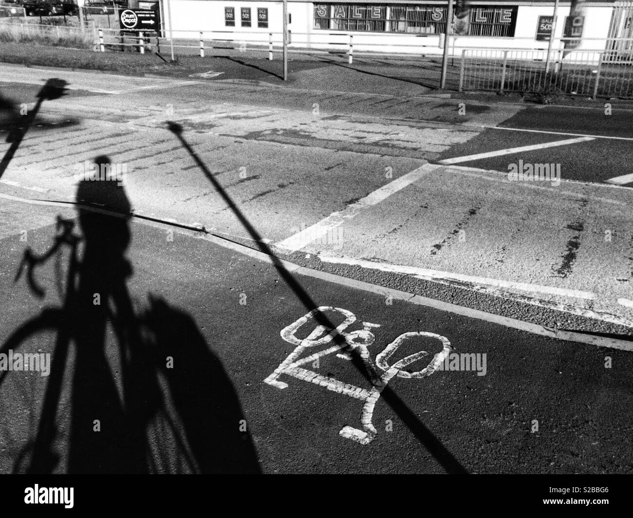 Schatten der ein Radfahrer von einem Radweg Kreuzung auf einer Hauptstraße. Stockfoto