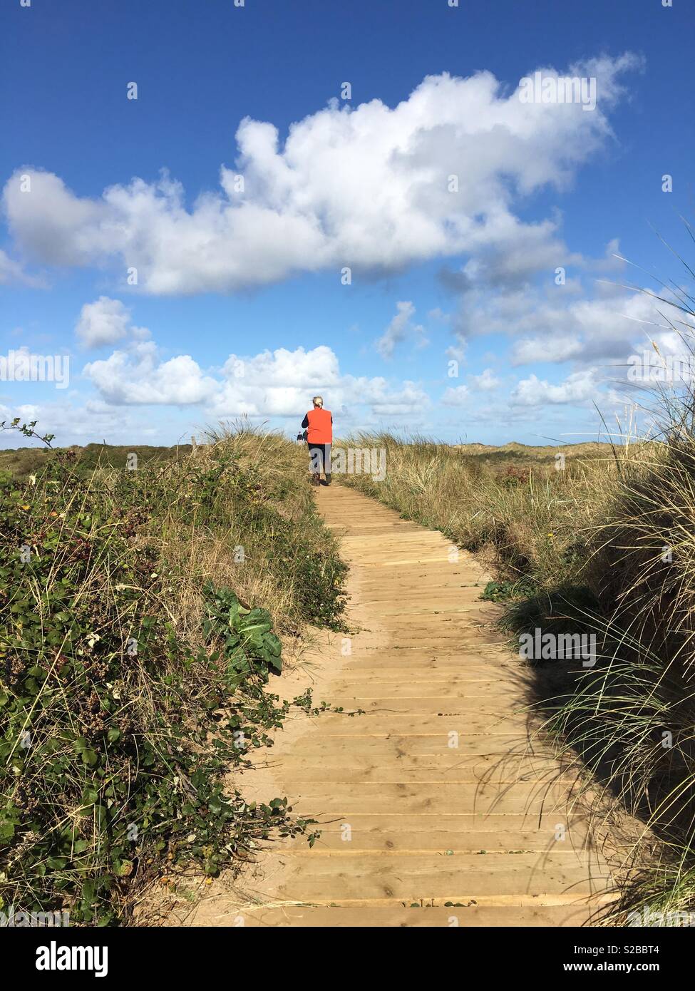 Eine junge Dame geht mitten unter einem Pfad über Sanddünen. Stockfoto