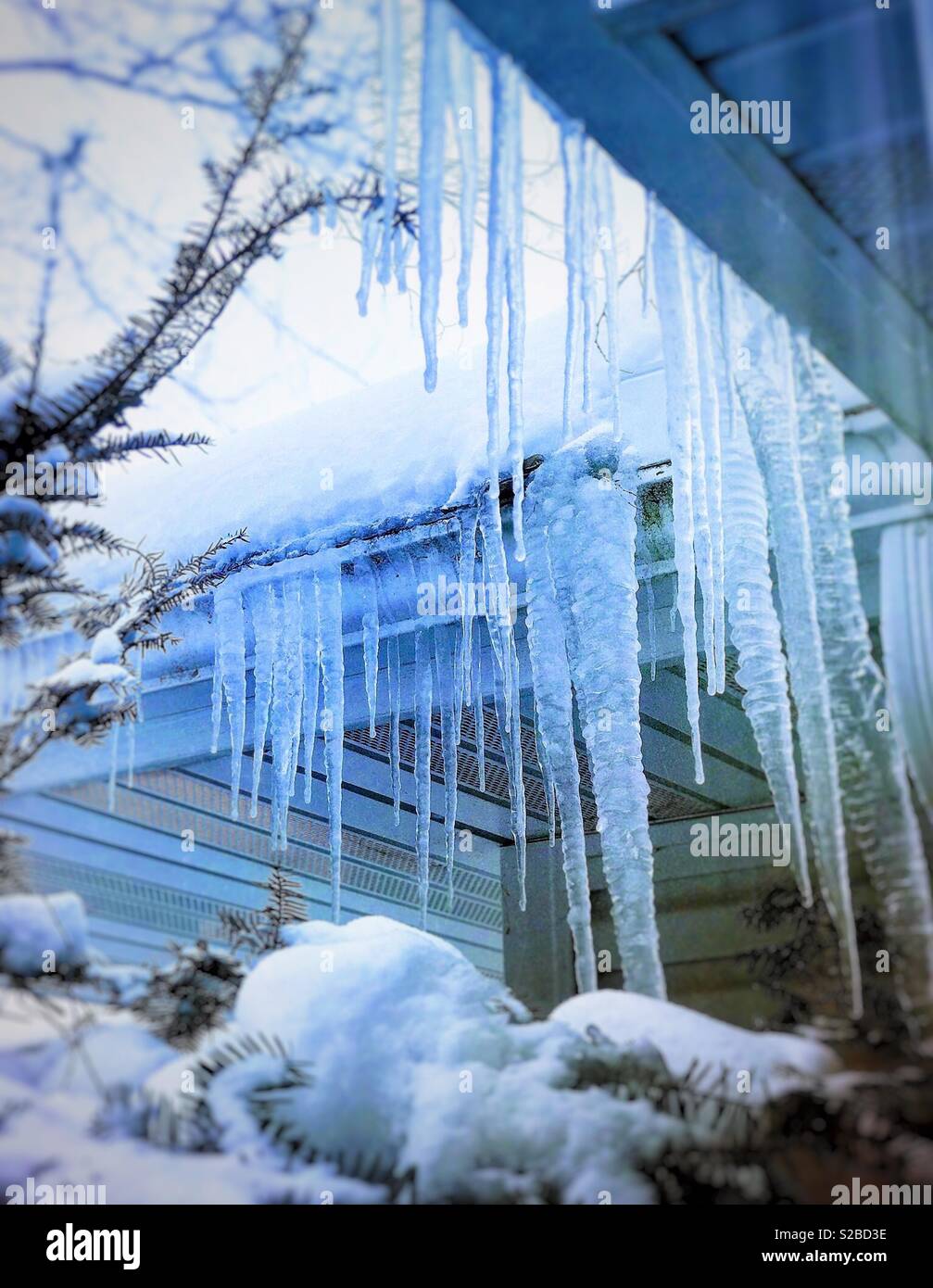 Eiszapfen hängen von der Traufe eines Hauses Stockfoto