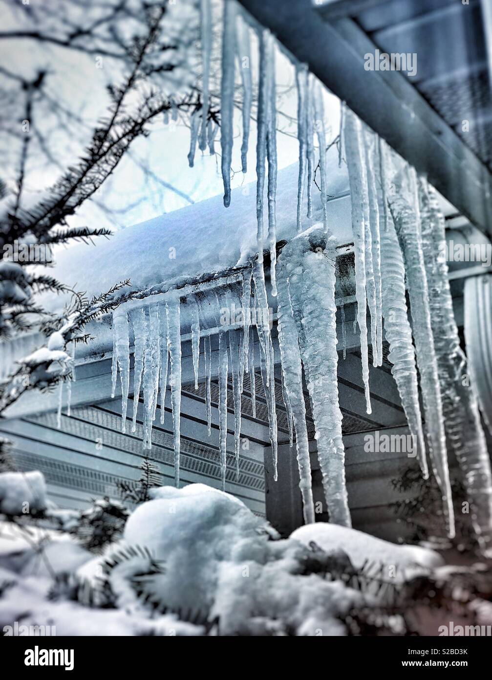 Eiszapfen hängen von der Traufe eines Hauses Stockfoto