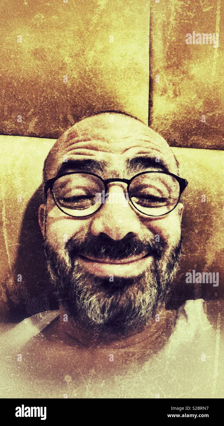 Erwachsener Mann, lustiges Gesicht während der Einnahme von selfie in seinem Bett - Smartphone-aufgenommenes Stockfoto