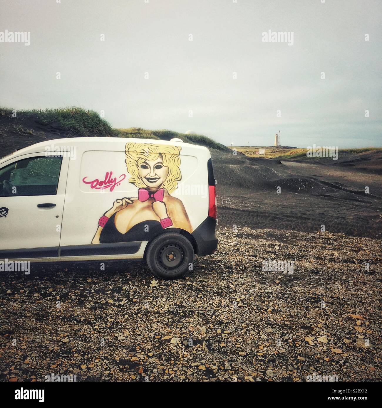 Ein Wohnmobil mit Mietwagen, der in der Landschaft Islands mit einer Dolly Parton Grafik geparkt ist - Island Tourismus Stockfoto