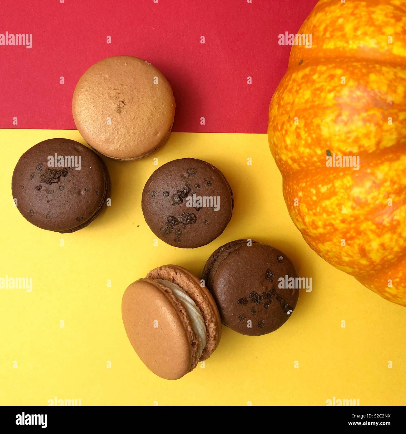 Herbst Genuss - Handgefertigte bunte Macarons zu den roten und gelben Hintergrund mit Kürbis Stockfoto