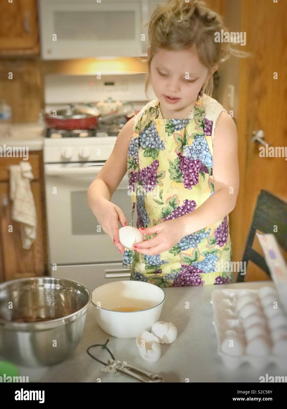 Kleines Mädchen rissen ein Ei für die Cupcakes sie bildet Stockfoto
