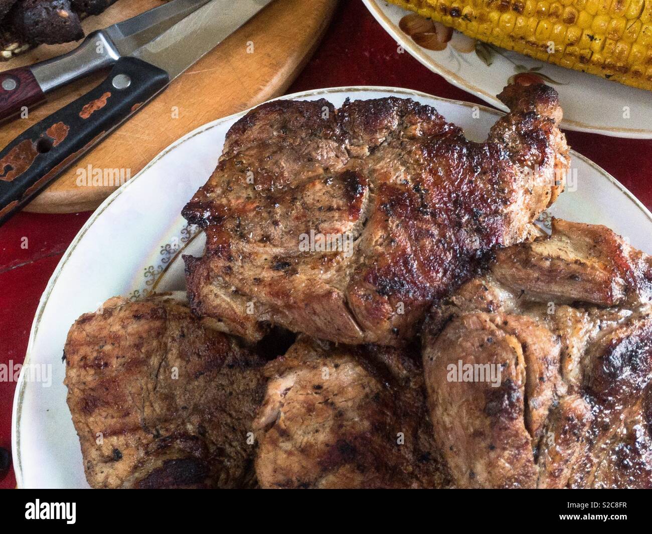 Eine Platte mit einem gegrillten Fleisch auf einem rustikalen Tisch - Smartphone-aufgenommenes Stockfoto