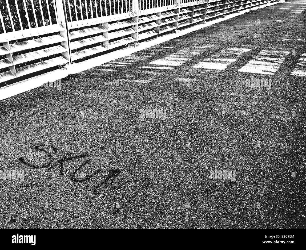 Fußgängerbrücke mit der Graffiti KUM', in Swindon, Wiltshire, UK, in Schwarz und Weiß. Platz kopieren Stockfoto