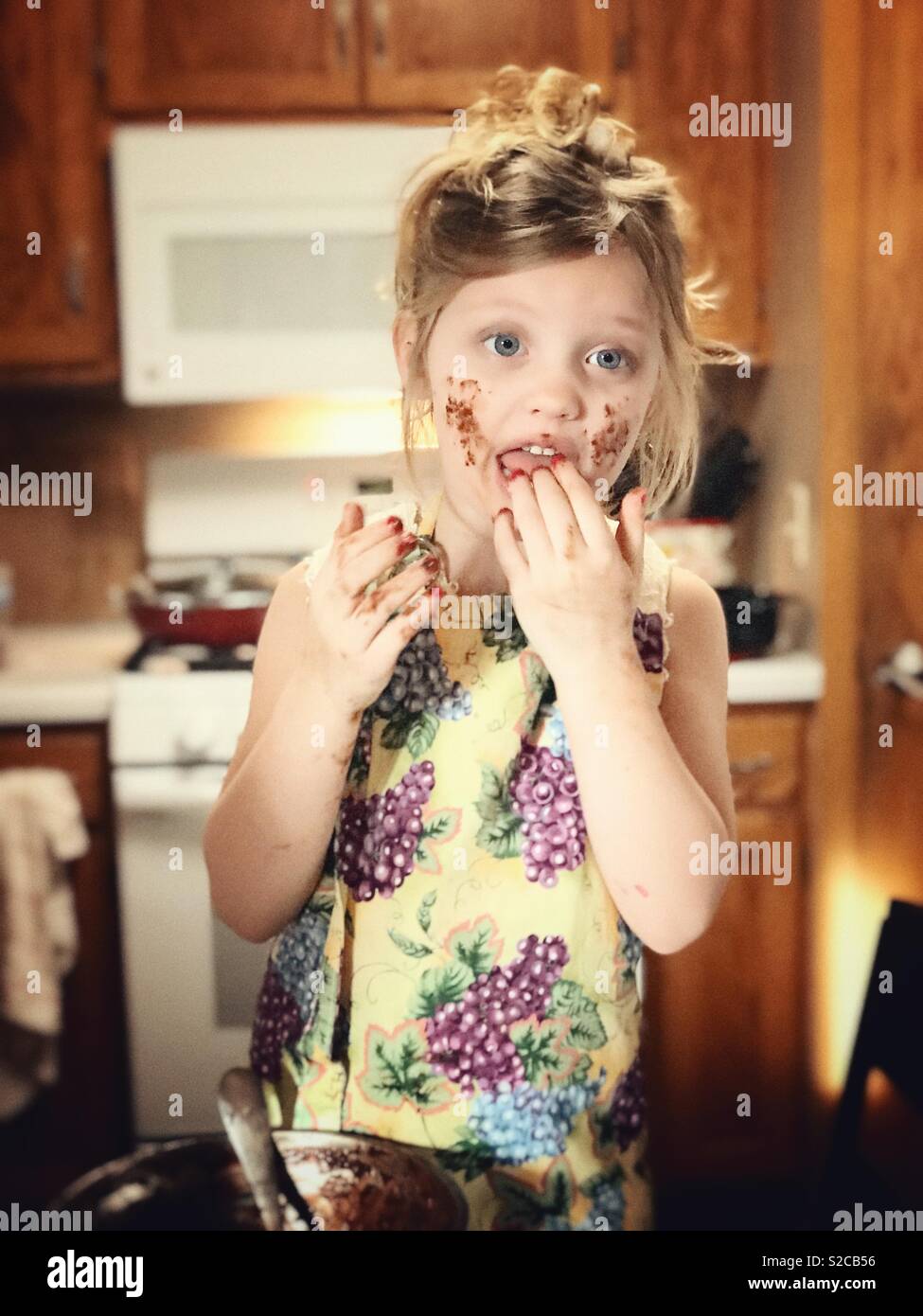 Kleines Mädchen schmeckende Schokolade ihre Finger nach dem Mischen der Batter Stockfoto