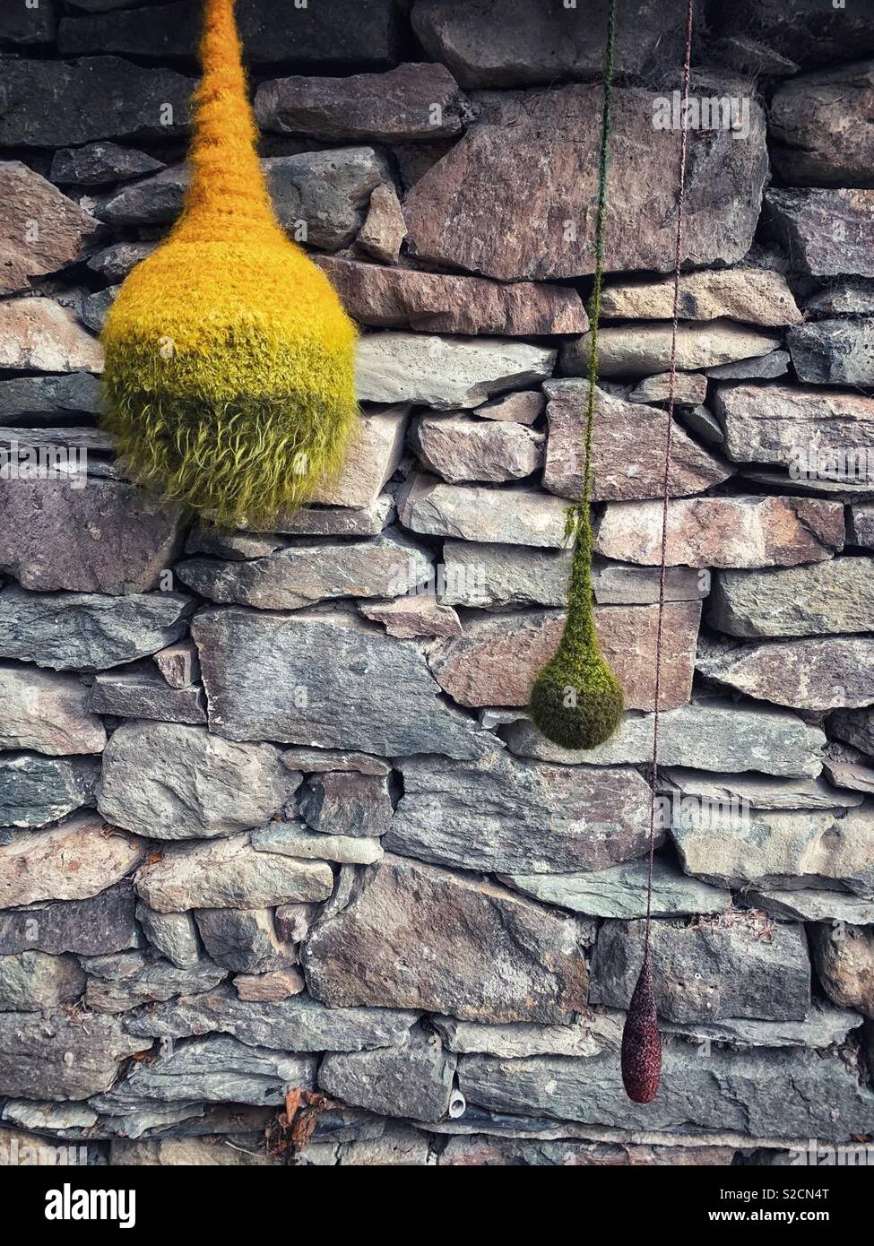 Einige Kunst aus der Landschaft gegen eine Steinmauer - Smartphone-aufgenommenes Stockfoto