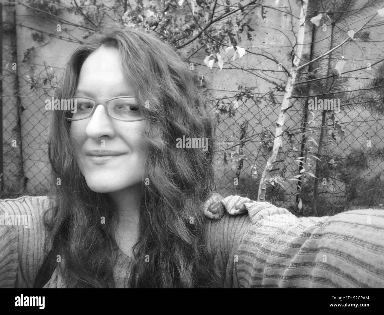 Selfie einer jungen Frau mit langen Haaren und Brille in Schwarz und Weiß Stockfoto
